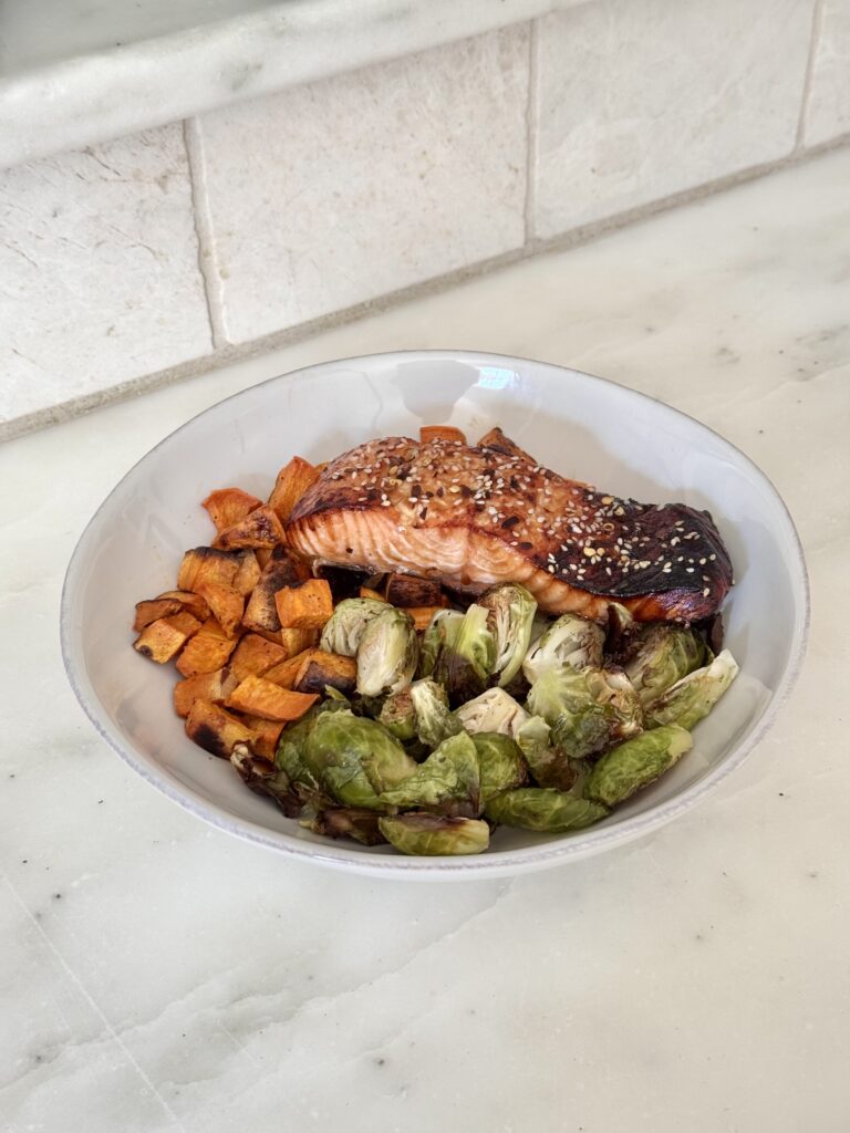 A beautifully baked Ginger Soy Salmon fillet, glazed with a savory tamari-based marinade, served on a white plate with a side of roasted vegetables. This gluten-free, high-protein dinner is the perfect choice for a quick and healthy weeknight meal.
