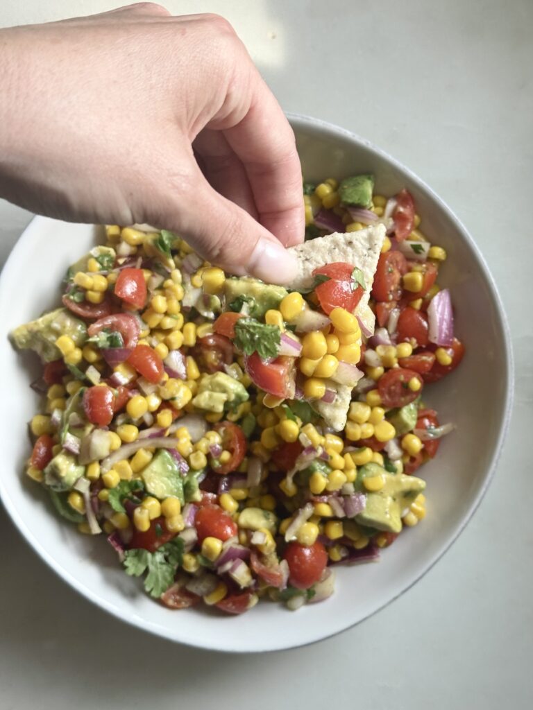 Homemade honey lime dressing with olive oil, garlic, and spices in a small bowl — perfect for avocado tomato corn salad.