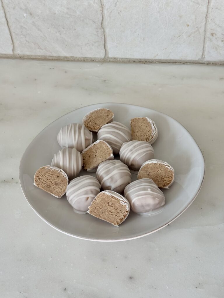 White Chocolate Chai Cake Balls made with oat flour, cashew butter, protein powder, and chai spices on a white plate with parchment paper