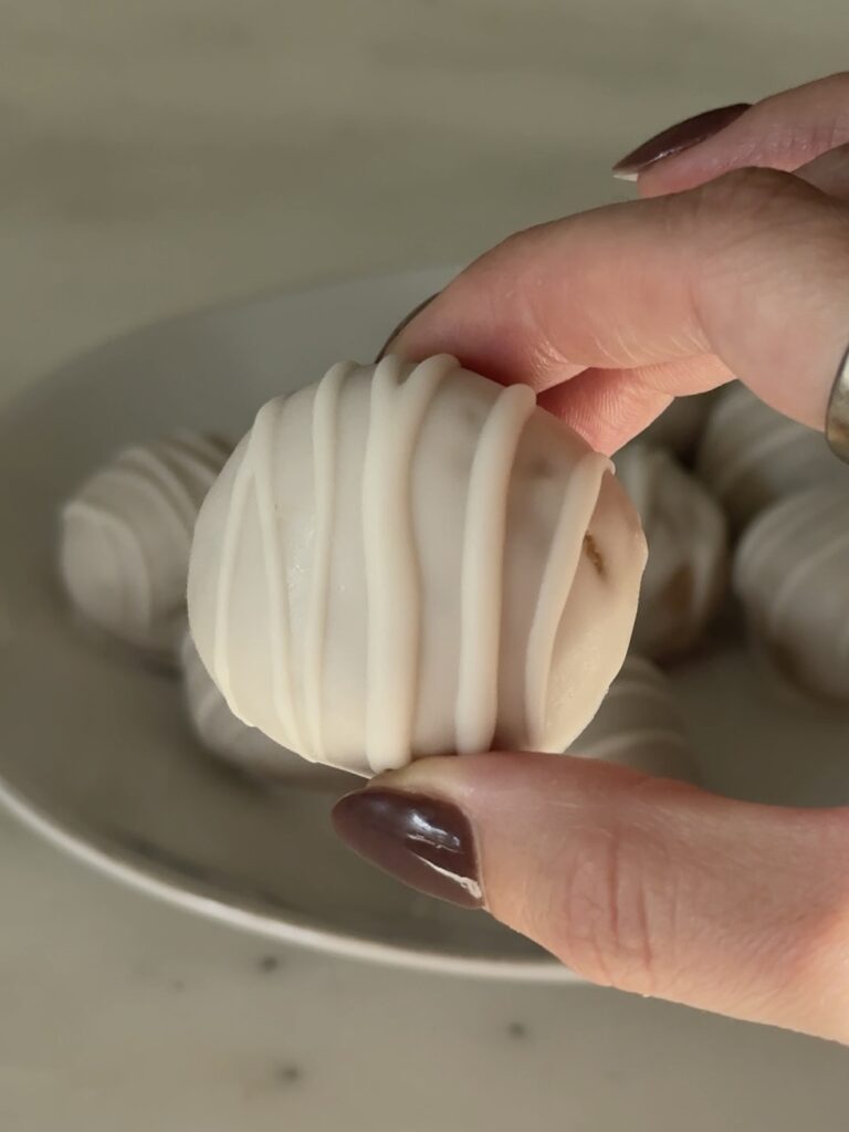 White Chocolate Chai Cake Balls on a plate with parchment paper, ready to serve, garnished with a drizzle of extra white chocolate
