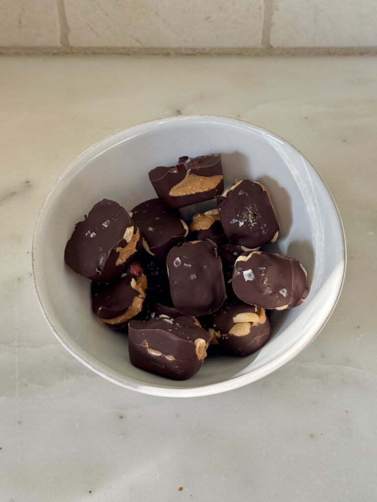 Completed vegan Mini Snickers bites served in a bowl, showing chocolate, peanut butter, and peanuts.
