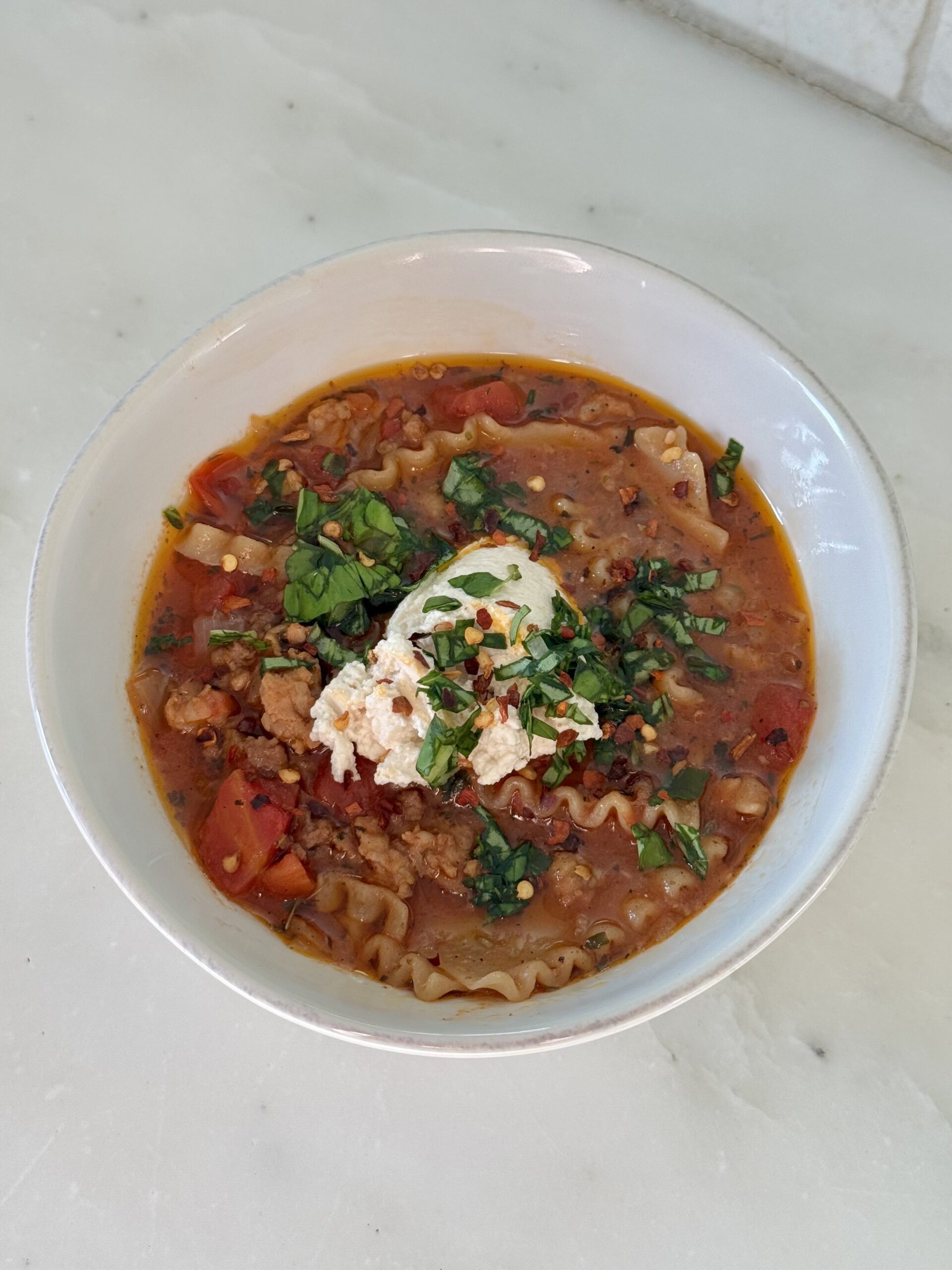 Bowl of one-pot thick lasagna soup with broken noodles, ground beef, and creamy broth