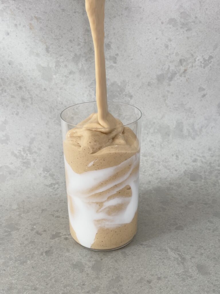 Pumpkin pie smoothie being poured from a blender into a glass