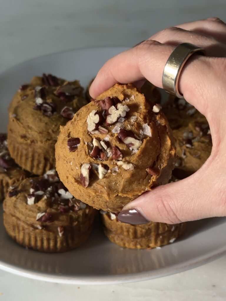 Single gluten-free pumpkin protein muffin with a golden top and pecan garnish, perfect for a healthy breakfast or snack
