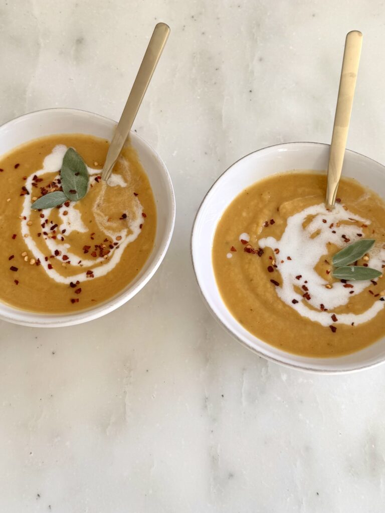 Close-up of dairy-free Sage Butternut Squash Soup in a white bowl with a smooth, creamy texture