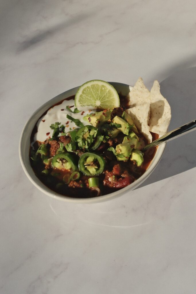 Finished bowl of high-protein one-pot chili topped with fresh garnishes.