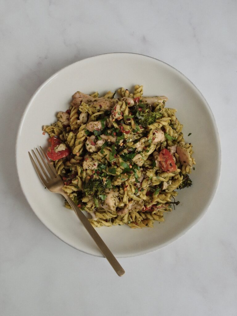 High-protein pesto chicken pasta made with gluten-free chickpea pasta, roasted chicken thighs, broccolini, and cherry tomatoes.