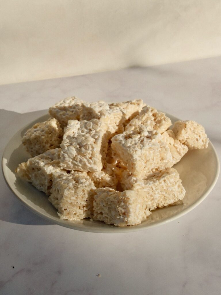Finished rice crispy treats cut into squares on a plate. 