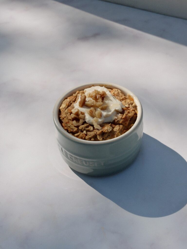 baked oats in ramekin with coconut yogurt and walnuts
