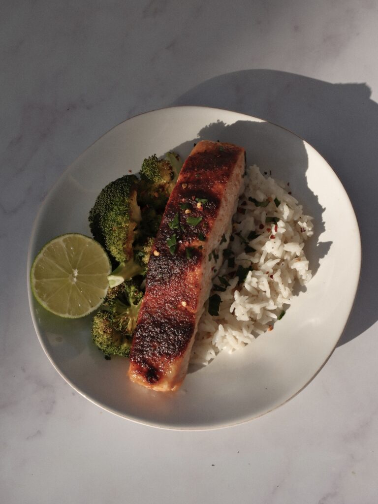 salmon served with broccoli, jasmine rice, cilantro and lime wedges